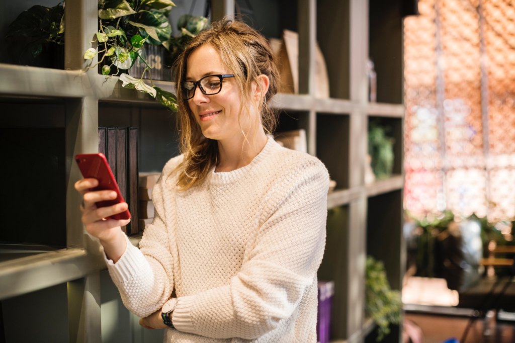 Woman entrepreneur holding iphone and smiling